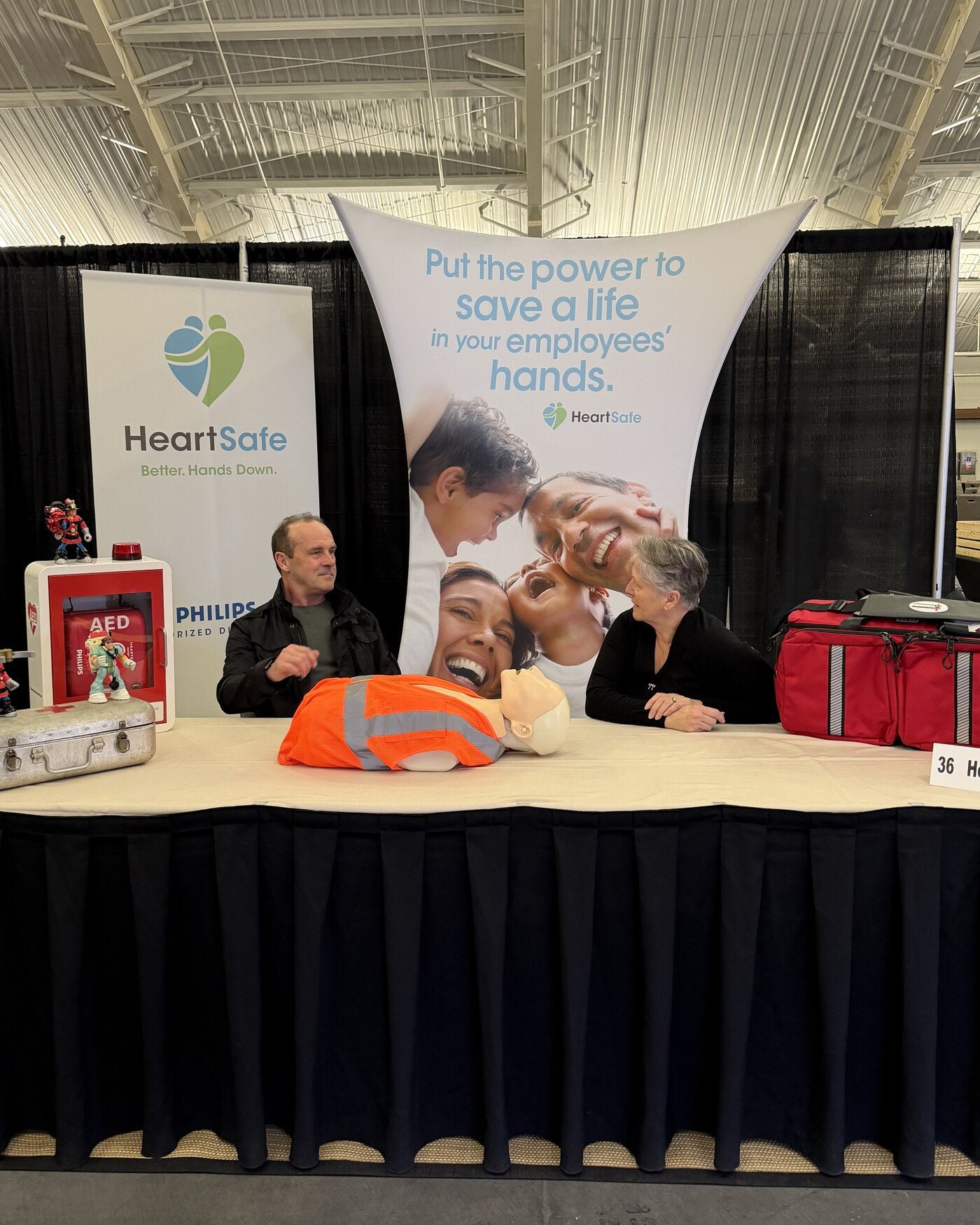 HeartSafe EMS booth with AED equipment, responder training gear, and Glenn and Deborah Burke